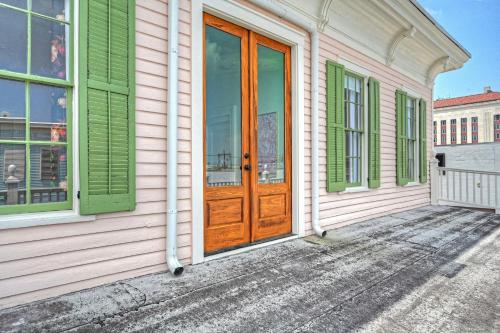 a pink house with a wooden door and green windows at Sugar's INN Room #1 in Galveston