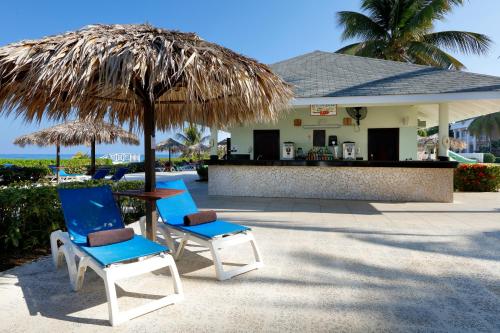 two chairs and a table under a straw umbrella at Grand Palladium Jamaica Resort & Spa All Inclusive in Lucea
