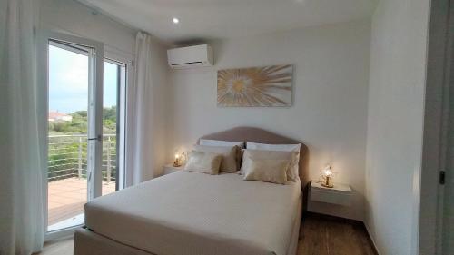 a white bedroom with a bed and a balcony at A.Mare in Stintino