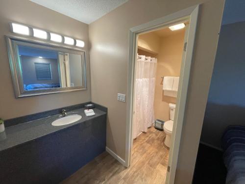 a bathroom with a sink and a mirror and a toilet at Scottish Inns Motel - Osage Beach in Osage Beach