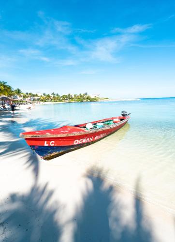 a red boat sitting on a beach next to the water at Grand Palladium Jamaica Resort & Spa All Inclusive in Lucea