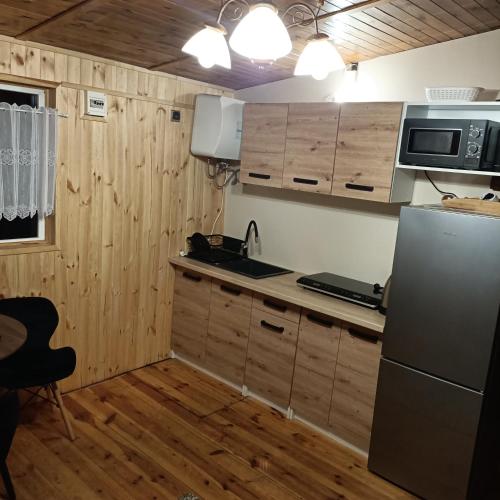 a kitchen with wooden cabinets and a refrigerator at Domek03 Osrodek Wypoczynkowy Joanna Wojowo in Kargowa