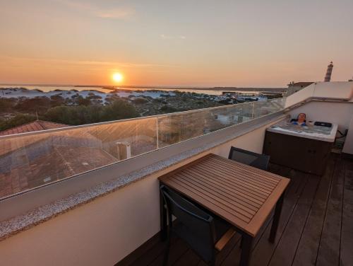 a balcony with a wooden table and a sunset at Casa Alegria Barra Deluxe by Home Sweet Home Aveiro in Praia da Barra