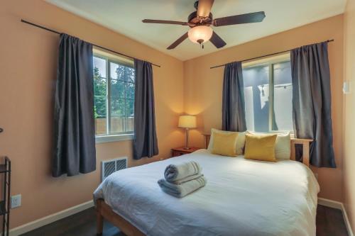 a bedroom with a bed with a ceiling fan and windows at Cozy Coeur dAlene Studio, Walk to Downtown and Lake in Coeur d'Alene