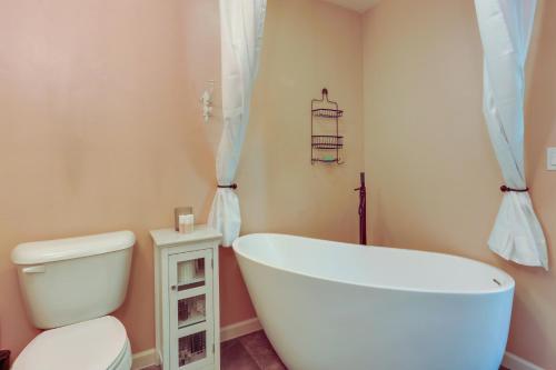 a bathroom with a white tub and a toilet at Cozy Coeur dAlene Studio, Walk to Downtown and Lake in Coeur d'Alene