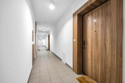 a hallway with white walls and a wooden door at Studio Groszowicka AC SWPS in Warsaw