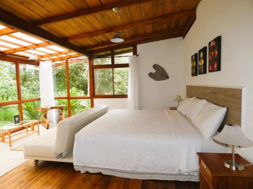 a bedroom with a large white bed and windows at San Isidro Lodge in Cosanga