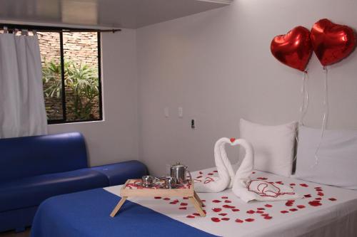 a room with a bed with two heart balloons at Pousada Maré Alta Maceió in Maceió