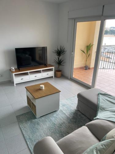 a living room with a couch and a tv at Aquamarine Sant Feliu en la playa con patio in Sant Feliu de Guixols