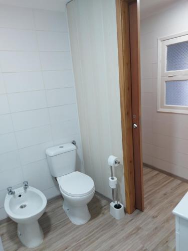 a white bathroom with a toilet and a sink at Casas da Tia Florinda - Casa Flor de Laranjeira in Faial da Terra