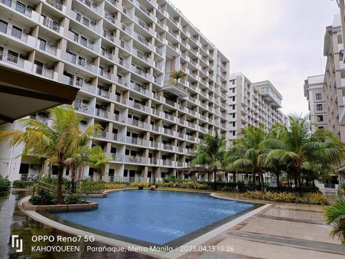 ein großes Apartmenthaus mit einem Pool und Palmen in der Unterkunft Spacious 1 BR condo unit Near NAIA in Manila