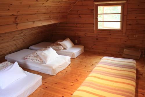 Habitación con 3 camas en una cabaña de madera en Guesthouse Teatime Cottage Pokhara, en Yamanakako