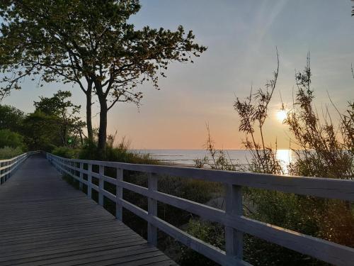 a wooden boardwalk leading to the beach at sunset at Arte Porta Mare in Kołobrzeg
