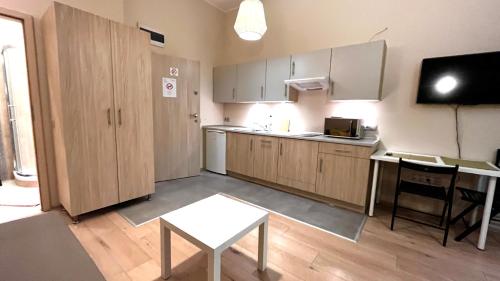 a kitchen with wooden cabinets and a table and a tv at Spacious Studio in Krakow