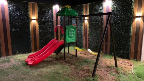 un parque infantil con un tobogán rojo y un columpio verde en شالية بونسيانا, en Tabuk