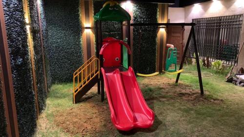 un parque infantil con un tobogán rojo en un edificio en شالية بونسيانا, en Tabuk