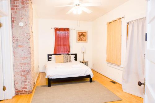 um quarto com uma cama e uma parede de tijolos em The Historic Cottage Screened Porch & Hammock em Columbia