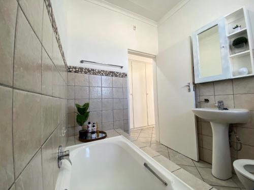 a white bathroom with a tub and a sink at Siena Sun Apartment 4 in Midrand