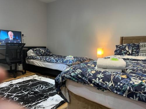 a bedroom with two beds and a tv in it at Grand Bleu - London - Next to Piccadilly Line Tube Station & Brand New Facilities in London