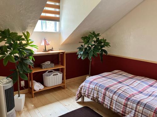 富士見町にあるジュリアンズイングリッシュホームステイアンドペンションのベッドルーム1室(ベッド1台、鉢植えの植物2本付)