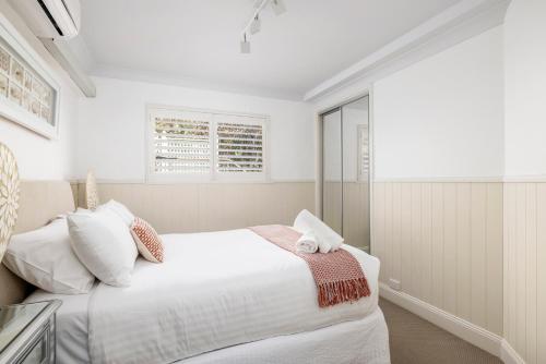 a white bedroom with a bed and a window at Yachtsman's Rest in Nelson Bay