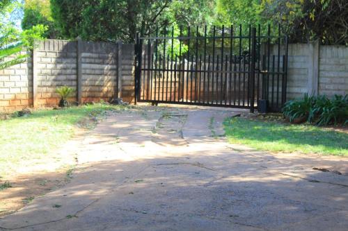 a driveway with a wrought iron gate in a yard at Kekeli B&B in Vryheid