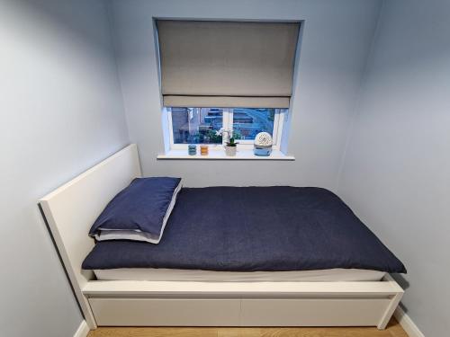 a bed with a blue blanket and a window at Joshua Court Single Room in Stoke on Trent