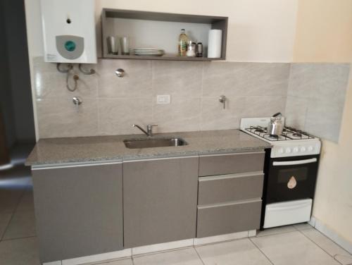 a kitchen with a sink and a stove at Depto Civora 2 in Villa Regina