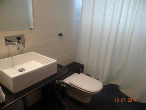 a bathroom with a white sink and a toilet at The Temple View Hotel in Shirdi