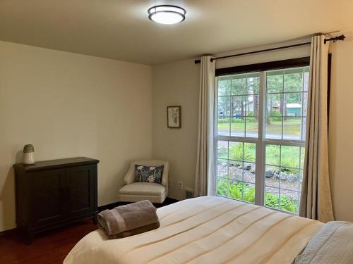 1 dormitorio con cama, ventana y silla en Forks Fir House en Forks