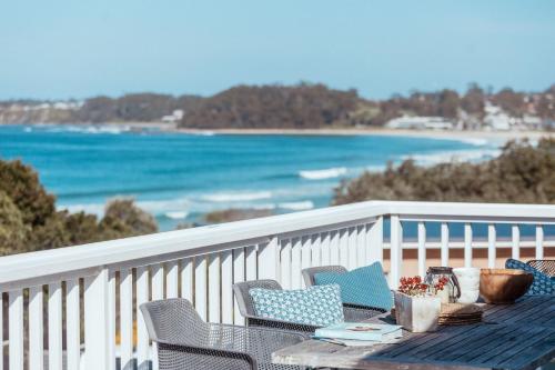a table on a balcony with a view of the beach at The Corner Cottage in Mollymook