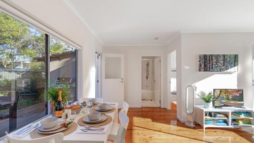 a dining room with a table and chairs and a large window at Kangaroo Cottage in Currarong