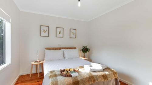 a white bedroom with a bed with a blanket at Kangaroo Cottage in Currarong