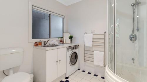 a white bathroom with a washing machine in it at Kangaroo Cottage in Currarong