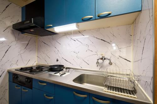 a kitchen with a sink and a stove and blue cabinets at Haneda Lex Apartment in Tokyo