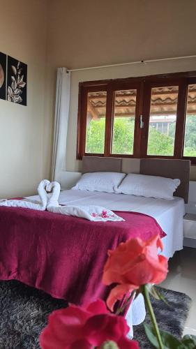 a bedroom with a bed with a red blanket and two windows at Belaninha in Guaramiranga