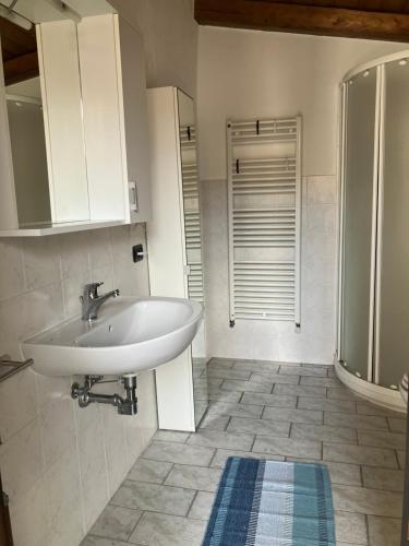 een badkamer met een witte wastafel en een douche bij UN PASSO DAL CASTELLO in Barolo