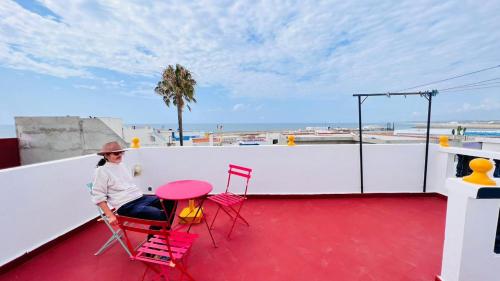 a woman sitting on a roof with a table and chairs at Dar Yema in Asilah