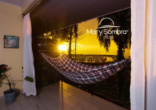 a hammock in a room with a view of the sunset at Mar y Sombra Villas in Quepos