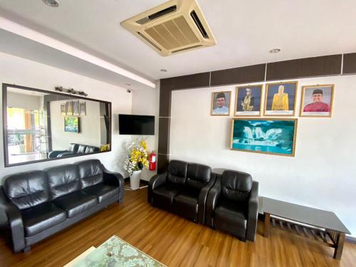 a living room with a black leather couch and a table at Rimaniz Hotel Alor Setar in Alor Setar