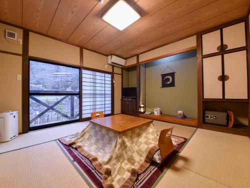 Habitación con mesa y algunas ventanas. en Sanso Matsuya, en Yufu