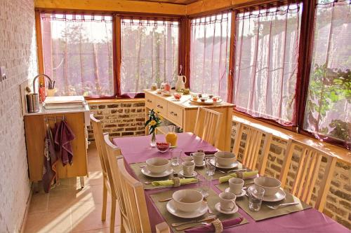 een eetkamer met een tafel, stoelen en ramen bij Huis van Rooi in Sint-Agatha-Rode