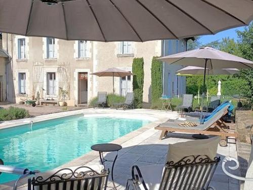 une piscine avec deux chaises et un parasol dans l'établissement Gîte 6 pers avec piscine, terrasse et parc, idéal randos et détente - FR-1-489-436, à Arfeuilles