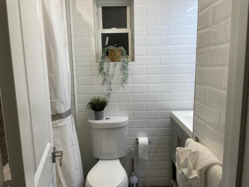 a white bathroom with a toilet and a window at Perfectly Located Modern 2BR w Priv Backyard in Brooklyn