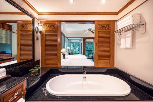 a bath tub in a bathroom with a bedroom at JW Marriott Phuket Resort and Spa in Mai Khao Beach