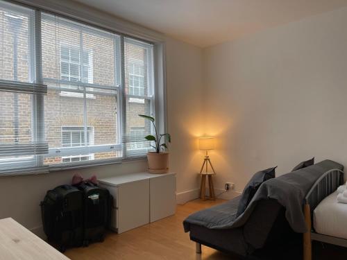 a bedroom with a bed and a chair and a window at Sootheus - Soho7 in London