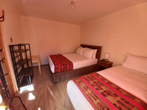 um quarto de hotel com duas camas e uma cadeira em hostal casa talitha em San Pedro de Atacama