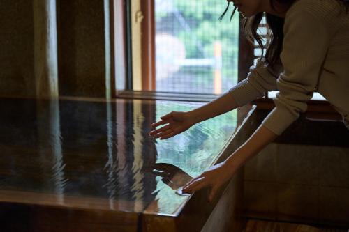 a woman is looking out of a glass window at Shima-Onsen Toshimaya in Nakanojo