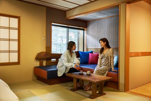two women sitting on a couch in a room at Shima-Onsen Toshimaya in Nakanojo