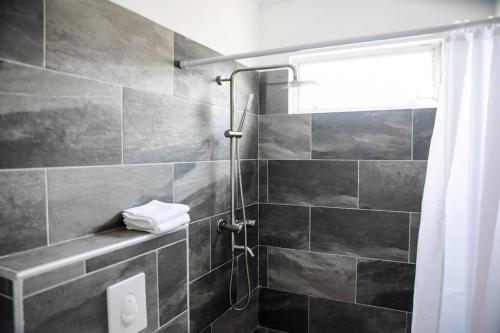 ein Bad mit einer Dusche mit schwarzen Fliesen in der Unterkunft Casa Grosso in Willemstad